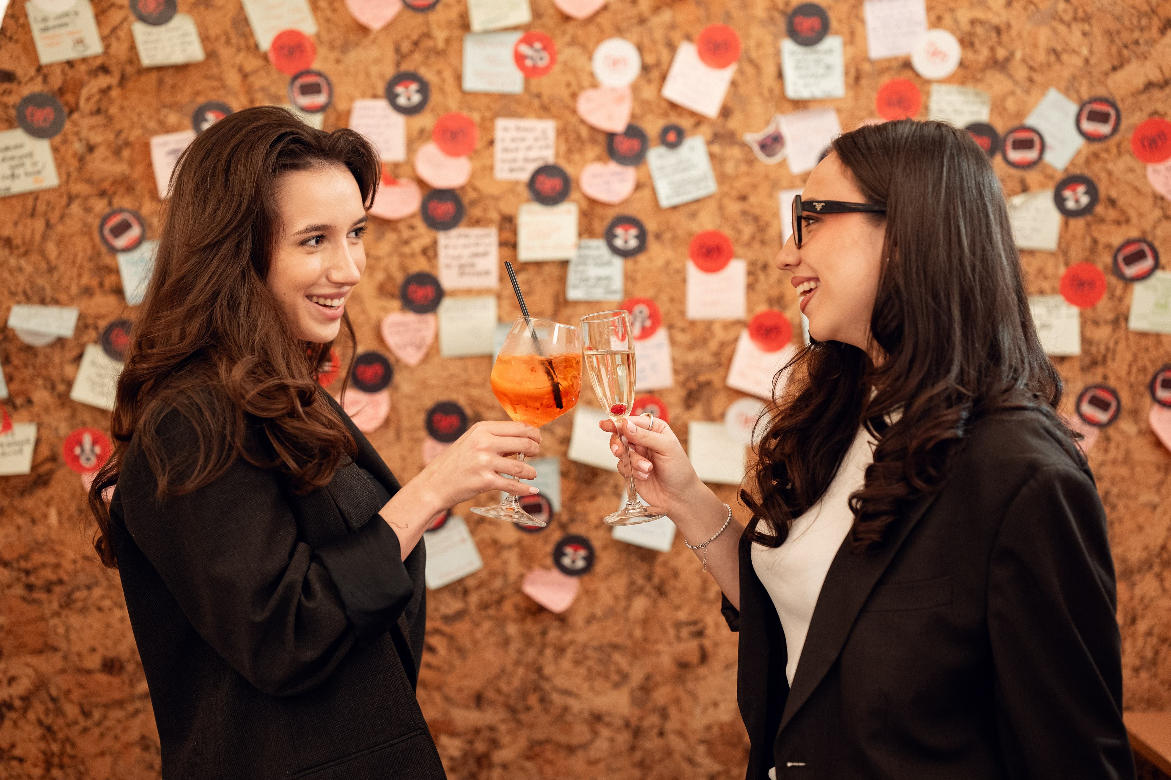 Cheers with cocktails in front of the Two Space community wall